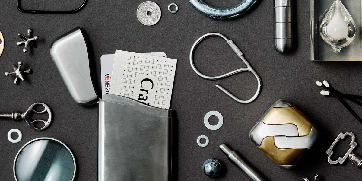 Everyday Carry Kollektion von Craighill: Karten-Etui aus Edelstahl, Schlüsselring, Taschenmesser und Metall-Objekte auf dunklem Grund